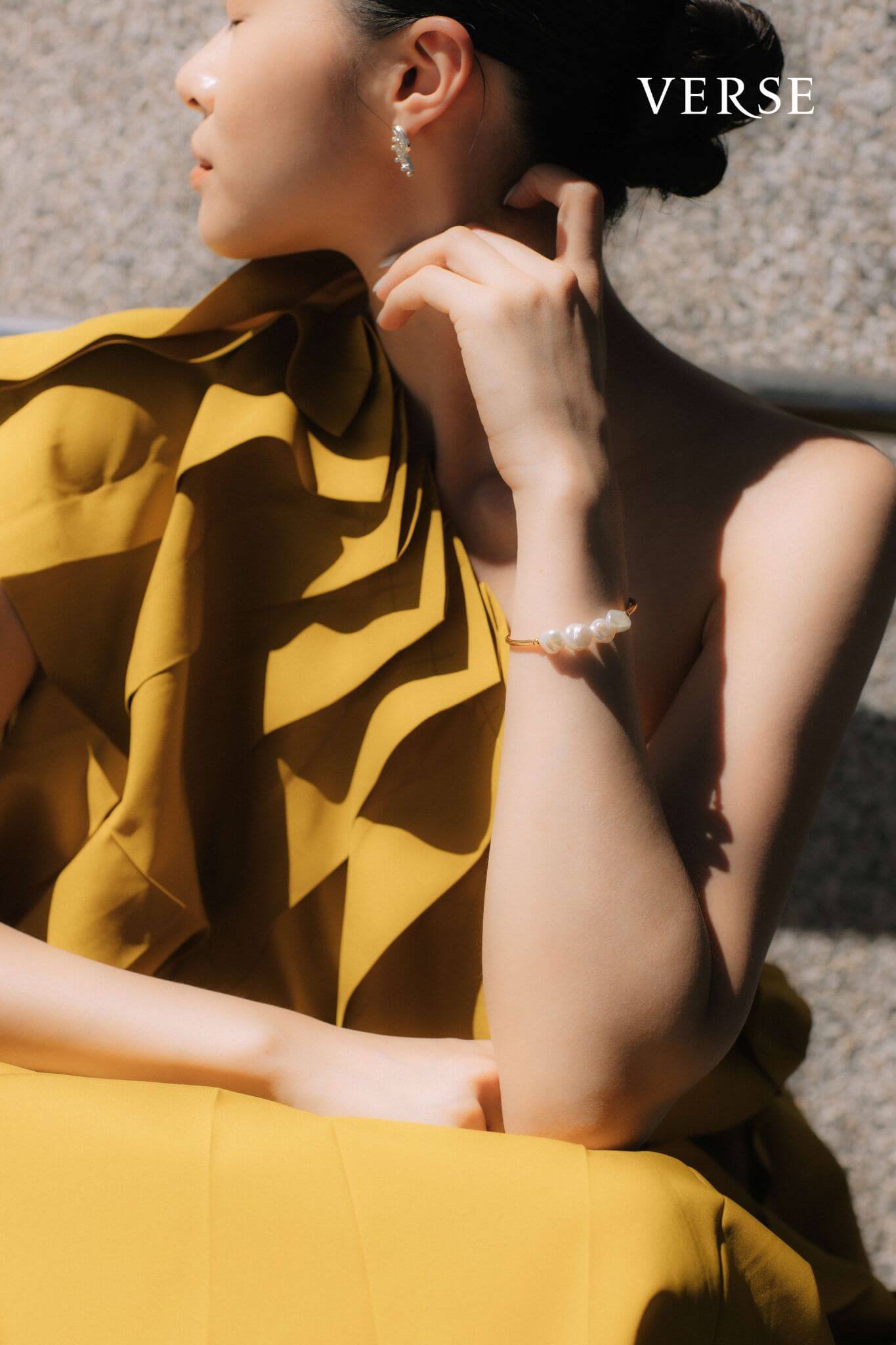 芥末黃斜肩長洋裝 by ISSEY MIYAKE；白色珍珠手環、銀色圖騰耳環 by agete