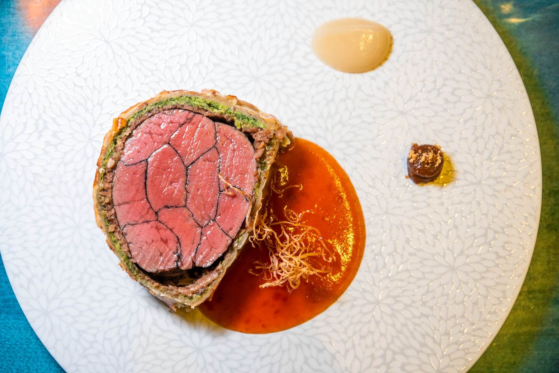 〈威靈頓台灣牛／豆瓣／甜醬油〉是以英國傳統威靈頓牛排結合台式豆瓣醬醃漬的台灣牛排，外層包裹菠菜千層麵皮，內餡是花菇、菜脯和高麗菜乾。