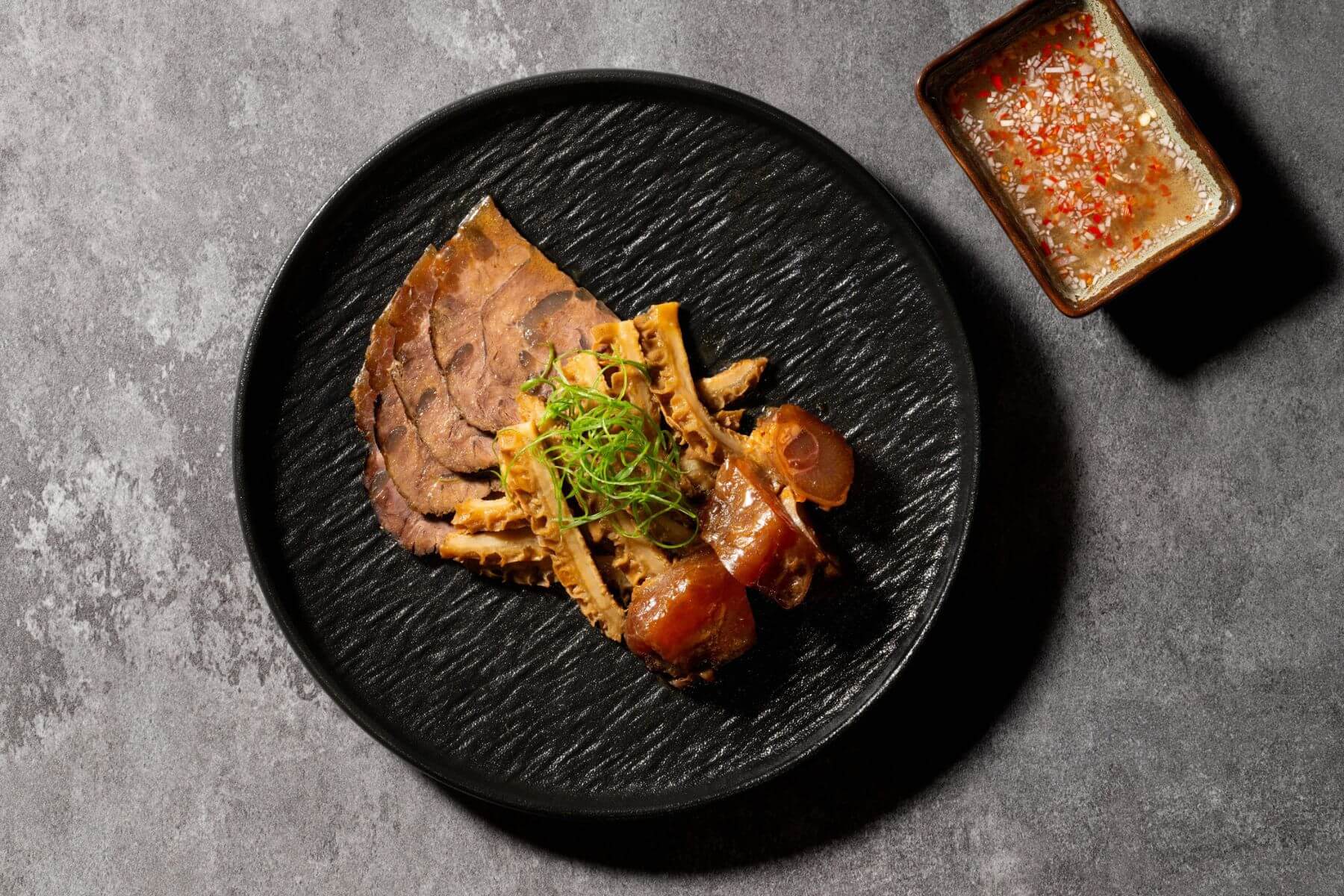 主廚以特製叉燒汁悉心慢滷牛腱、牛肚、牛筋打造「牛三寶」，佐以香蒜辣椒醋。