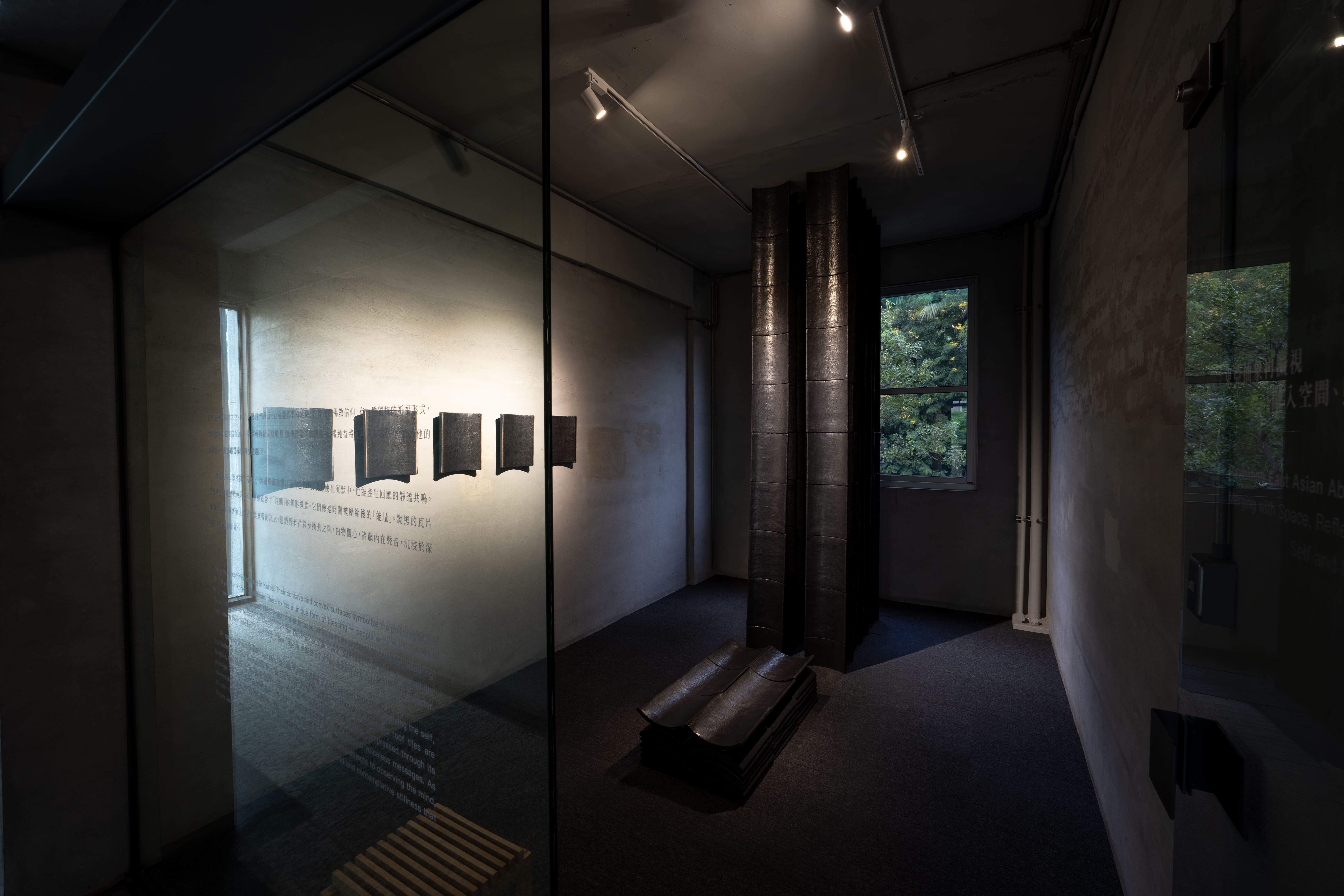 權純益以近十年每日反覆塗抹的石墨瓦片，在展間築造頂天觸地的巨型石碑；在光線照耀下，墨面如「心鏡」般由黯轉明，帶領觀者沿著墨韻光點走入藝術家的內在心畫。