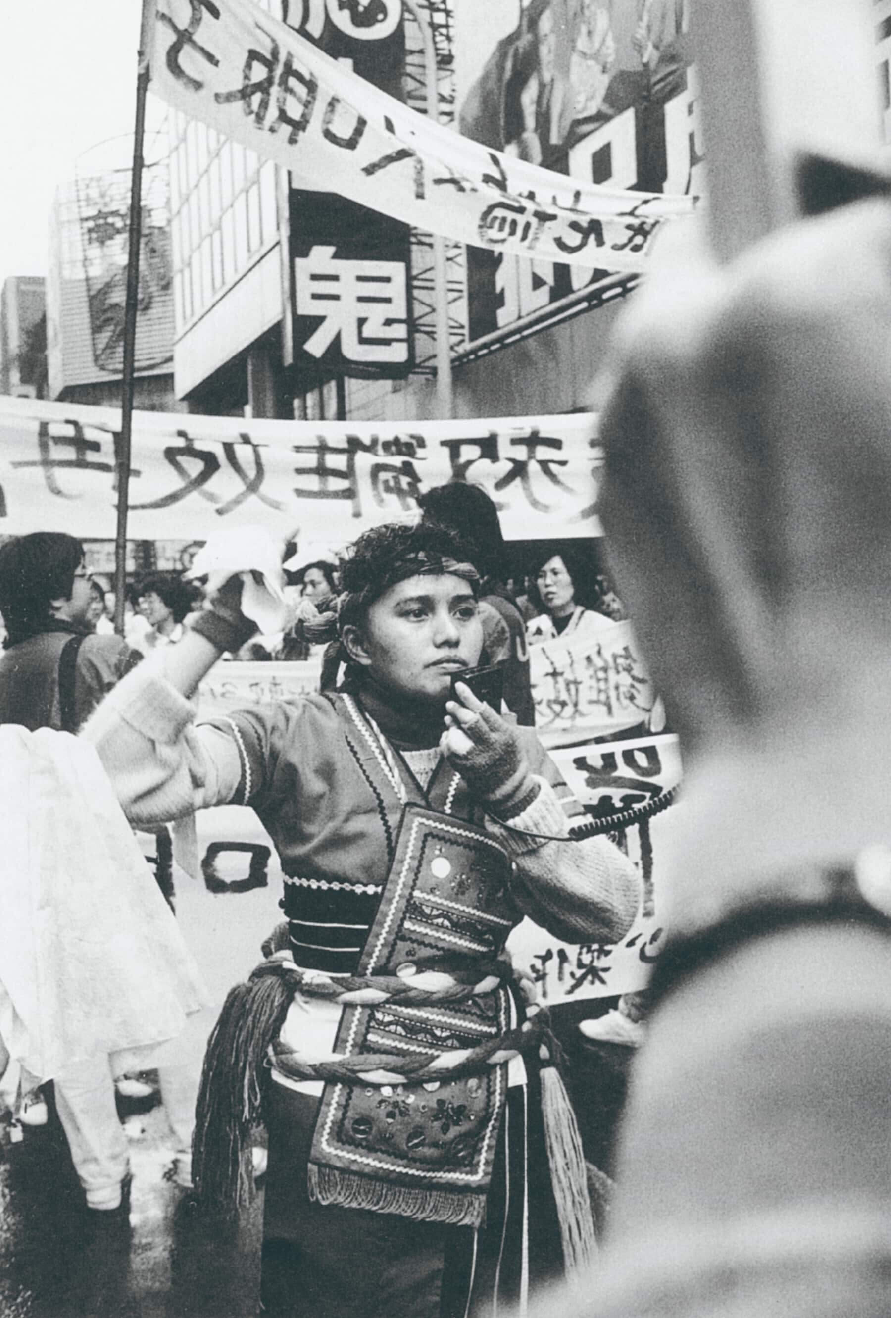 1987年臺北反雛妓大遊行中，簡扶育拍下身穿傳統服飾的羔露．瑪萊（漢名：陳美珠）拿起大聲公，用阿美族語對