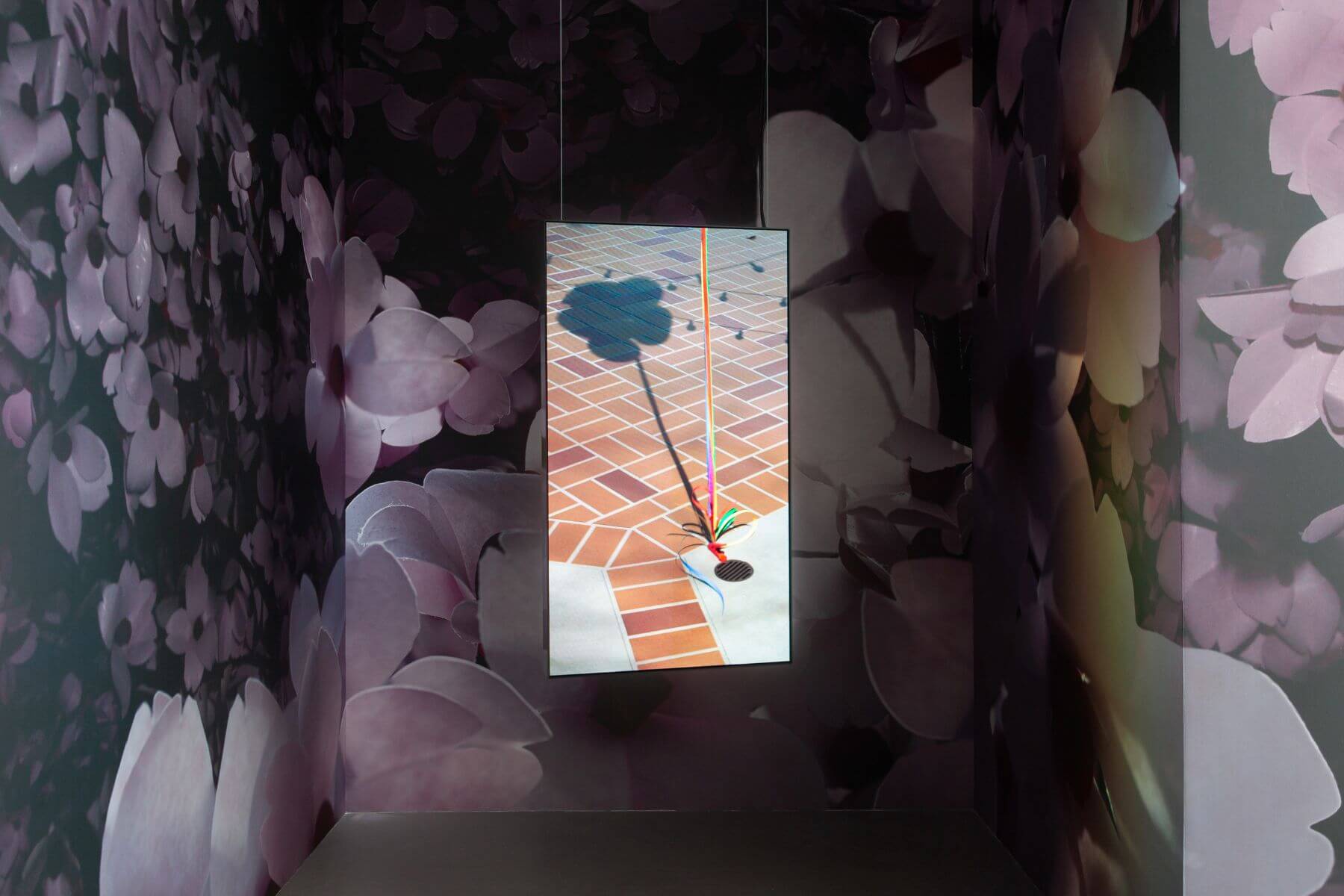 動態影像作品《氣球》(2018)中,僅見夾子、五顏六色的絲帶,氣球本身卻漂浮在畫面之外,透過投射在地面的影子顯現。(圖/臺北市立美術館提供)